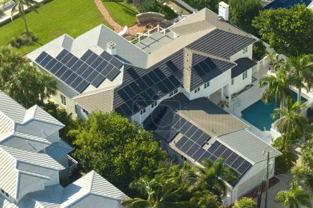 Téléchargez les photos : Vue aérienne d'une maison américaine coûteuse avec piscine et toit avec panneaux solaires photovoltaïques bleus pour produire de l'énergie électrique écologique propre. Electricité renouvelable avec concept zéro émission. - en image libre de droit