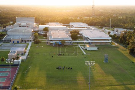 Öffentliche Schulsporthalle in North Port, Florida, mit Schulkindern, die American Football im Rasenstadion spielen. Konzept für Aktivitäten im Freien.