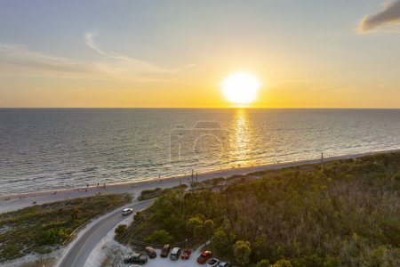 Photo for Parking lot at Blind Pass beach on Manasota Key in Englewood. Tourists cars in front of ocean beach with soft white sand in Florida. Popular vacation spot at sunset. - Royalty Free Image