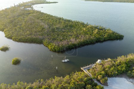 Half sunken sailing yacht capsized on shallow bay waters after hurricane Ian in Manasota, Florida.