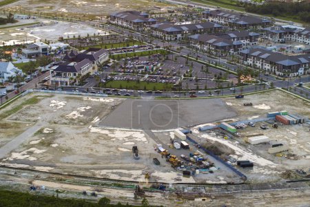 Construction site with building equipment on prepared ground in american suburbs. Aerial view of large development area of residential housing. Real estate market in the USA.