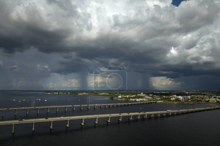 Stormy clouds forming from evaporating humidity of ocean water before thunderstorm over traffic bridge connecting Punta Gorda and Port Charlotte over Peace River. Bad weather conditions for driving.