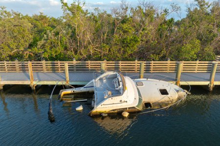 Aerial view of sunken sailboat on shallow bay waters after hurricane in Manasota, Florida.