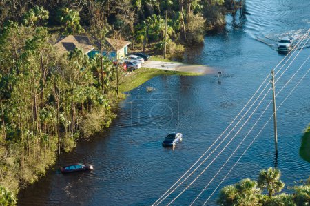 Flooded road in Florida after heavy hurricane rainfall. Aerial view of evacuating cars and surrounded with water houses in suburban residential area.