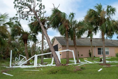 Les dommages causés par l'ouragan à la clôture blanche de la cour arrière en PVC ont été ruinés après que des débris d'arbres y soient tombés en Floride.