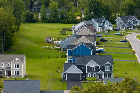 Low-density two story private homes in rural residential suburbs outside of Rochester, New York. Upscale suburban houses with large lot size and green grassy lawns in summer season.