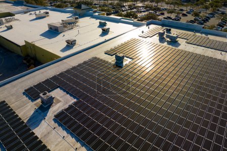 Production of sustainable energy. Aerial view of solar power plant with blue photovoltaic panels mounted on industrial building roof for producing green ecological electricity.