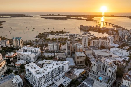 Sarasota Bay marina with luxury yachts and Florida city architecture at sunset. High-rise office buildings in downtown district. Real estate development in Florida. USA travel destination.