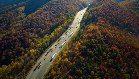I-40 freeway in North Carolina leading to Asheville through Appalachian mountains in golden fall with fast moving trucks and cars. Interstate transportation concept.