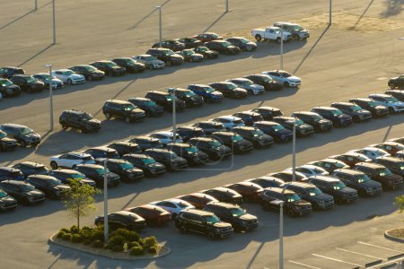 Large parking lot of local dealer with many brand new cars parked for sale. Development of american automotive industry and distribution of manufactured vehicles concept.
