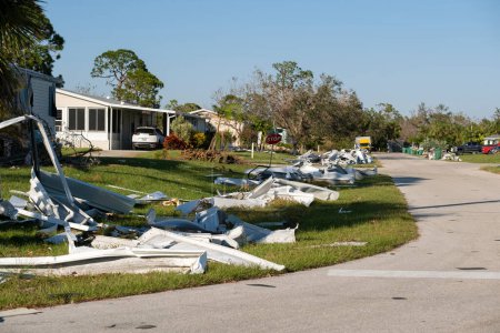 Scrap metal disposed in heaps on street side after hurricane severely damaged houses in Florida mobile home residential area. Consequences of natural disaster.