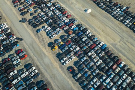 Blick von oben auf einen großen Parkplatz mit geparkten Gebrauchtwagen nach einem Unfall, der zum Verkauf bereit steht. Auktionshändlerfirma verkauft gebrauchte defekte Fahrzeuge zur Reparatur.