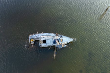 Aerial view of sunken sailboat on shallow bay waters after hurricane in Manasota, Florida.