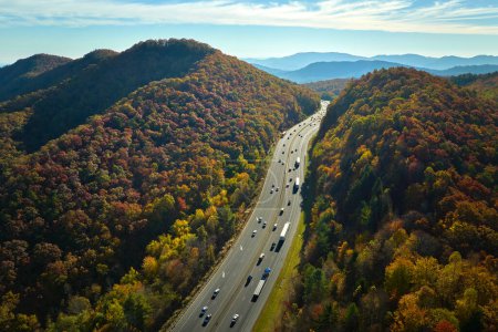 Vista desde arriba de la autopista I-40 en Carolina del Norte rumbo a Asheville a través de las montañas Apalaches en temporada dorada de otoño con camiones y coches de conducción rápida. Concepto de transporte interestatal.