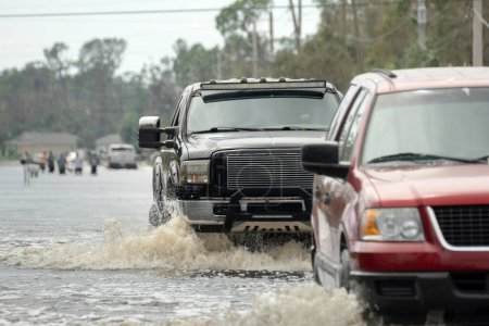 Flooded street after hurricane rainfall with driving cars in Florida residential area. Consequences of natural disaster.
