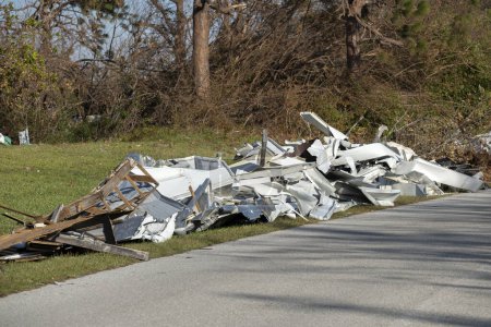 Piles of rubbish on street side from severely damaged houses after hurricane in Florida mobile home residential area. Consequences of natural disaster.