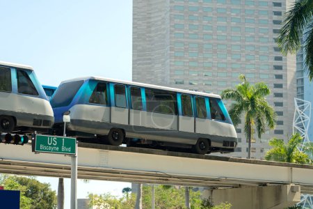 City train car on high railroad over street traffic between skyscraper buildings in modern American megapolis. Urban transportation in downtown district of Miami Brickell in Florida USA.