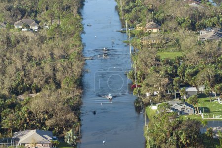 Flooded american street with moving vehicles and surrounded with water houses in Florida residential area. Consequences of hurricane natural disaster.