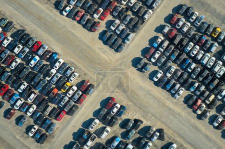 Blick von oben auf einen großen Parkplatz mit geparkten Gebrauchtwagen nach einem Unfall, der zum Verkauf bereit steht. Auktionshändlerfirma verkauft gebrauchte defekte Fahrzeuge zur Reparatur.