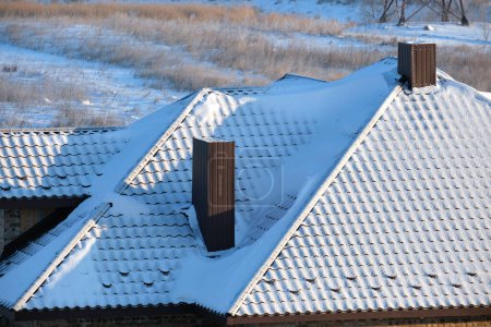 Schneeschutz für die Sicherheit im Winter auf dem Dach des Hauses, das mit Stahlschindeln abgedeckt ist. Fliesenverkleidung des Gebäudes.