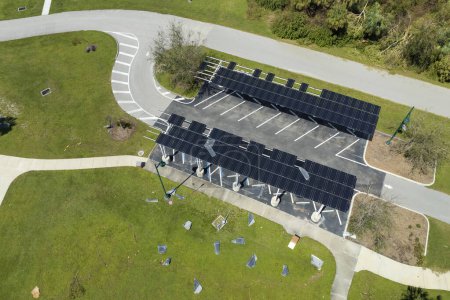 Versagen der Photovoltaik-Technologie, die in die städtische Infrastruktur integriert ist. Hurrikan-Windschaden an Sonnenkollektoren als Schattendach über Parkplatz für geparkte Elektroautos installiert.