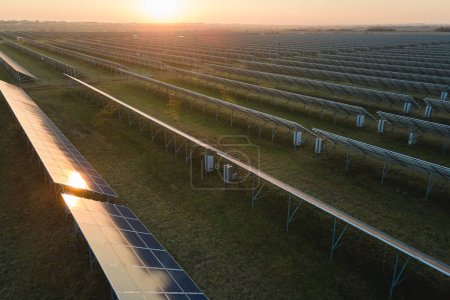 Luftaufnahme eines großen nachhaltigen Kraftwerks mit vielen Reihen von Photovoltaikmodulen zur Erzeugung sauberer elektrischer Energie bei Sonnenuntergang. Erneuerbarer Strom mit Null-Emissions-Konzept.