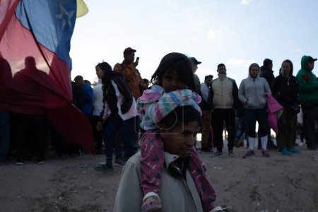 Foto de Juárez, México, 15-11-2022: Padre lleva a su hija sobre sus hombros en el campamento para migrantes venezolanos instalado en la frontera entre Juárez y El Paso Texas, los migrantes esperan en el campamento el fin del título 42. - Imagen libre de derechos