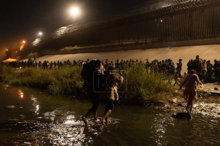 Foto de Juárez, México, 11-12-2022: 1400 migrantes, en su mayoría de Bolivia y Nicaragua, cruzan la frontera en una caravana en Juárez para rendirse a la patrulla fronteriza y solicitar asilo humanitario. - Imagen libre de derechos