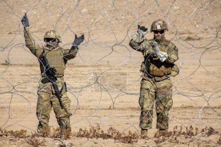 Foto de Juarez, Mexico, 12-21-2022: Texan National Guard places wire and barbed wire on the banks of the Rio Grande to prevent migrants from crossing into the United States to request humanitarian asylum. - Imagen libre de derechos