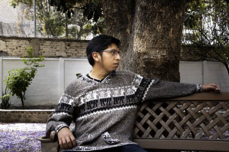 Foto de Hombre latino con suéter de lana sentado en un banco - Imagen libre de derechos