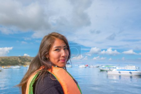 Foto de Smiling young latin woman sightseeing in a boat on the shores of lake titicaca in bolivia - Imagen libre de derechos