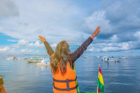 Foto de Young woman with arms up admiring and enjoying lake titicaca in - Imagen libre de derechos