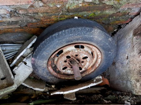 Foto de Llantas del coche viejo, plano y agrietado, oxidado a través de la pared de ladrillo - Imagen libre de derechos