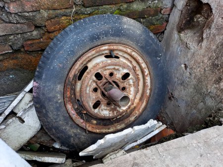 Foto de Llantas del coche viejo, plano y agrietado, oxidado a través de la pared de ladrillo - Imagen libre de derechos