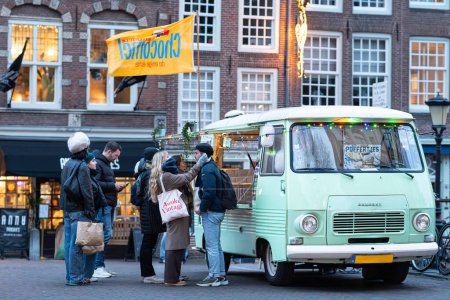 Photo for Utrecht, Netherlands - December 03, 2023: A Dutch 'Poffertjeskraam' Selling Chocomel and Poffertjes During Winter December Period with Couple in Scarf and Gloves - Royalty Free Image