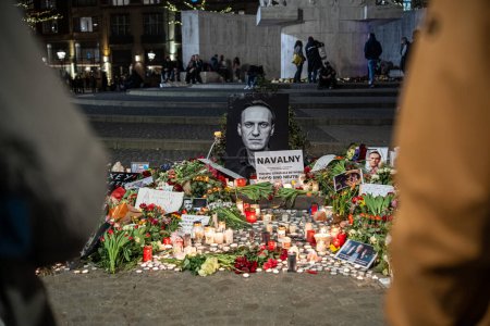 Foto de Ámsterdam, Países Bajos - 17 de febrero de 2024: Conmemoración improvisada de la muerte Alexei Navalny en la plaza Dam con velas y flores - Imagen libre de derechos