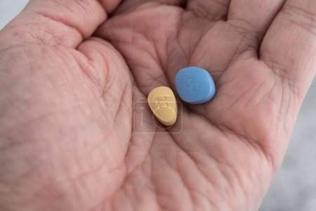 Zwei blaue und braune Pillen in der Hand des Mannes. Männergesundheit, Medikamente zur Erektion, Behandlung der erektilen Dysfunktion