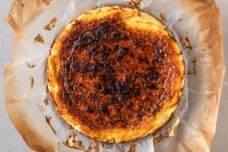 Téléchargez les photos : Gâteau au fromage brûlé basque entier San Sebastian dans un plat de cuisson sur une table en béton. vue de dessus. De la nourriture espagnole. Petit déjeuner savoureux - en image libre de droit