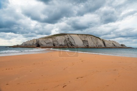 Téléchargez les photos : Isla del Castro avec plage de sable fin Covachos, Santander, Cantabrie, Espagne. Île rocheuse et crache sablonneuse par temps nuageux. Destination de voyage populaire sur les vacances - en image libre de droit