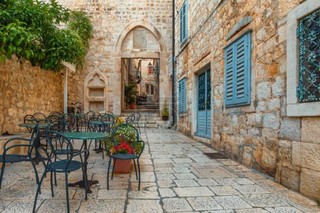 Cafe Tische und Stühle draußen in der alten gemütlichen Straße in der alten mittelalterlichen Stadt Hvar in Outdoor-Restaurant mit niemandem, Dalmatien, Kroatien. Beliebtes Reise- und Touristenziel im Sommerurlaub.