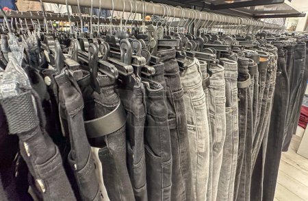 Photo for Grey and black jeans on the hangers in the clothes shop. Black denims in the shop. Trousers. - Royalty Free Image