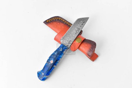 A Damascus bladed knife with blue handle and leather sheath against a white background.