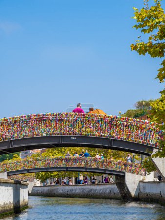 Photo for Tourists taking photos and looking at the canal from the arched bridge full of colored strips in the Portuguese Venice of the town of Aveiro - Royalty Free Image