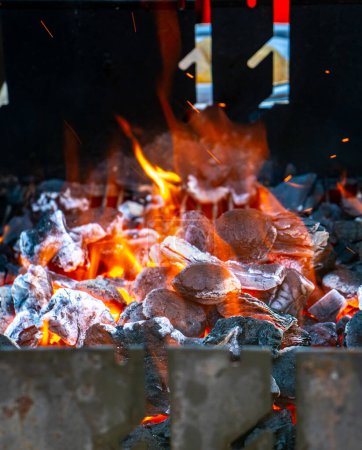 Photo for Charcoal and embers burning at full capacity at its peak in a metal barbecue and smoke - Royalty Free Image