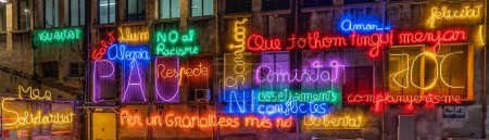 Photo for Illuminated letters and words made with neon lights and LEDs of many colors with words in the Catalan language with evocative concepts of hope and wishes on a wall of an abandoned factory. Banner - Royalty Free Image