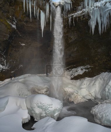 Photo for Group of mountaineering tourists behind the frozen Kvernufoss waterfall, with snow and stalagmites with the water falling into the frozen rivers of Iceland - Royalty Free Image