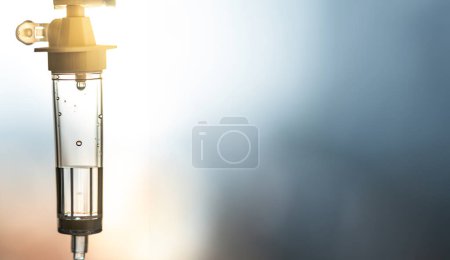 Foto de Quimioterapia y goteo intravenoso vitaminas atención médica. IV goteo en primer plano con efecto bokeh y retroiluminado con el resplandor del sol y la iluminación fluorescente por detrás. - Imagen libre de derechos