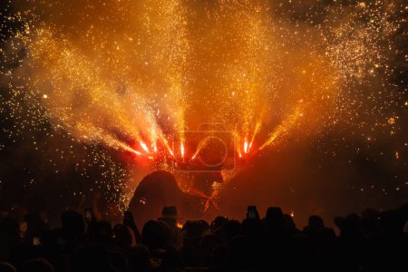 Photo for Dragon performing a pyrotechnic show from his head in Correfoc and Devils in granollers during the traditional major festival. People record with their mobile phones and dance under the fire and the s - Royalty Free Image