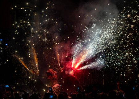 Photo for Mythical dragon dancing in a pyrotechnic show with fireworks shooting from its head during the traditional festival. People record with their mobile phones. - Royalty Free Image