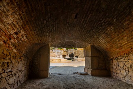 Photo for Interior with the vaulted ceiling of medieval Roman bricks of a gladiator room or beast cage with the view of the arena of the Merida amphitheater and its entrances with arched doors. - Royalty Free Image